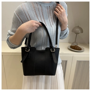 Detail of black pebble leather texture and gold hardware on a chic bucket bag