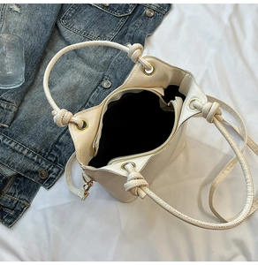 Detailed view of the off-white bucket bag interior with black lining and zipper pocket