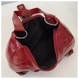 Detail view of red pleated handbag with metal ring, zipper closure and black lining interior