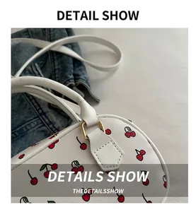 Detailed close-up of white PU leather bag featuring vibrant red cherry patterns and gold hardware