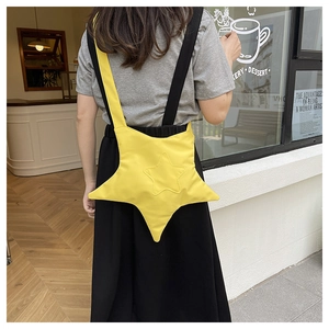 Vue de rue d'un sac à bandoulière en toile jaune en forme d'étoile avec sangle contrastée