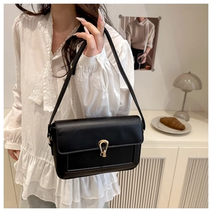 Detail of black faux leather shoulder bag with adjustable strap and gold metal buckle