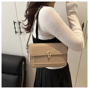 Close-up of beige leather shoulder bag with lychee texture and gold metal buckle detail