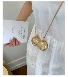 Dettaglio della mini borsa dorata a forma di arachide con strass e catena sottile