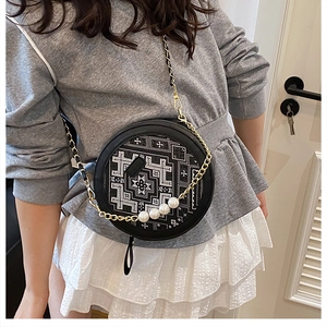 Detailed view of the round crossbody bag featuring ethnic patterns and pearl accents