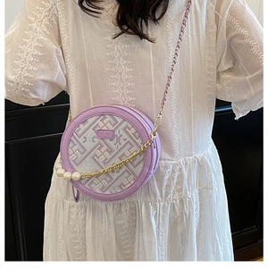 Detail of round purple crossbody bag with floral embroidery and large pearl accents