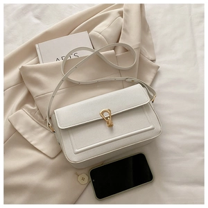 Detailed macro view of white pebble leather texture and gold horseshoe buckle on handbag