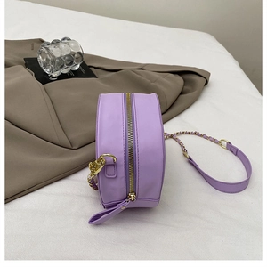 Detail der hellvioletten runden Tasche mit goldenem Reißverschluss und Kettenriemen