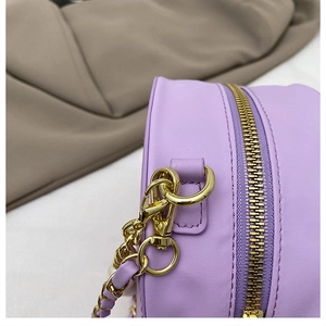 Detailansicht der lavendelfarbenen runden Tasche mit goldenem Reißverschluss und Naht
