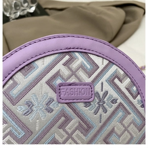 Nahaufnahme der fliederfarbenen Sticktasche mit geometrischem Muster und Leder-FASHION-Tag