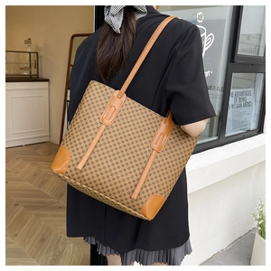 Detail of retro patterned tote bag with leather shoulder straps shown on a model