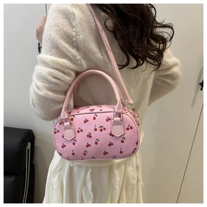 Detail of pink Boston bag with cherry print shown on a model against white wall