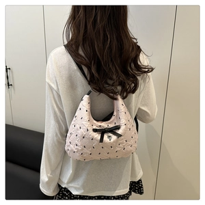 Détail du sac matelassé rose avec motifs de lapins noirs et un nœud en ruban de soie