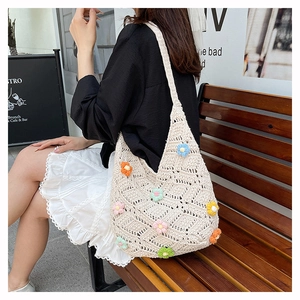 Close-up of beige crochet tote bag with colorful 3D floral accents and diamond mesh pattern