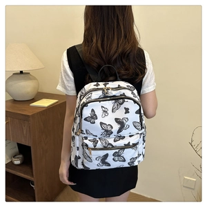 Detail view of stylish white backpack with black butterfly print on a female model