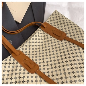 Detail of vintage beige tote bag showing geometric floral print and brown leather handles