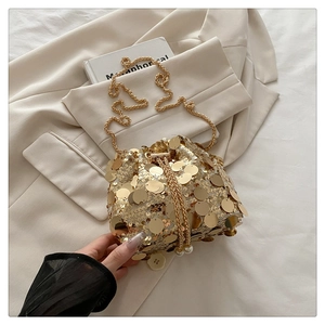 Detail of gold sequin bucket bag with metal chain strap and pearl drawstring closure