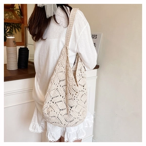 Détail d'un sac à bandoulière en crochet crème avec des motifs floraux tricotés ajourés