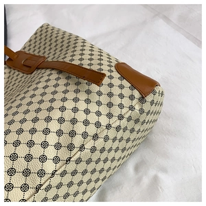 Detail of vintage-style tote bag with clover patterns and premium brown leather trim