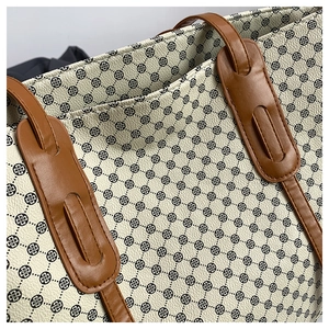 Detailed close-up of clover pattern on cream tote bag with premium leather stitching