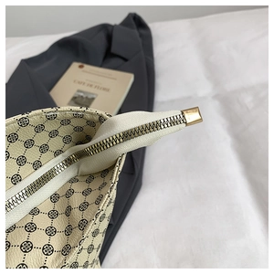 Detail of clover print handbag featuring premium leather texture and golden metal zipper