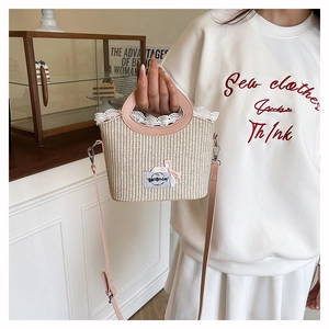 Détail du sac à main en paille avec bordure en dentelle rose et logo de marque