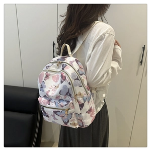 Side view of a white backpack featuring colorful butterfly prints and gold zippers on a model