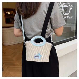 Détail d'un sac en paille beige avec bordure en dentelle blanche et nœud bleu en plein air