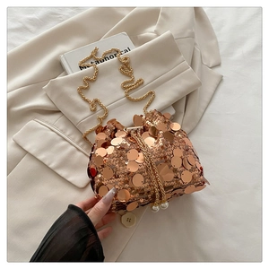 Detailed shot of rose gold sequin bucket bag with gold chain and pearl drawstrings