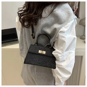 Detail of black glitter crossbody bag with golden twist lock and textured finish