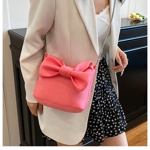 Sac rose avec nœud et chaîne porté par un mannequin dans un cadre intérieur