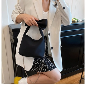 Fashionable black bow handbag with silver chain strap shown in a modern lifestyle setting