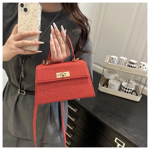 Detail of red glitter mini handbag with golden turn-lock and metallic textured finish