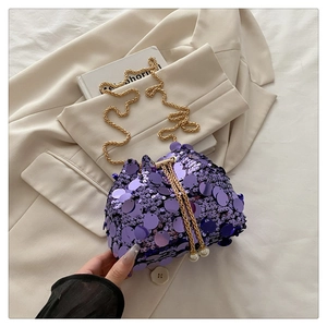 Detailed close-up of purple sequined bucket bag with gold chain and pearl drawstrings