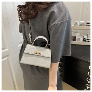 Detailed side view of silver glitter crossbody bag featuring gold twist lock hardware
