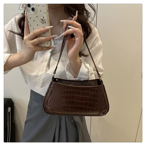 Detail of dark brown baguette bag featuring vintage crocodile embossed leather texture
