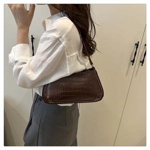 Detail of vintage brown crocodile embossed baguette bag with sleek shoulder strap