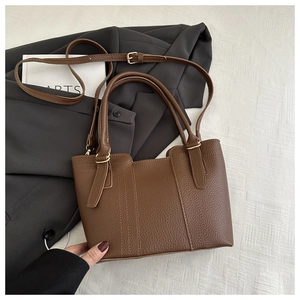 Detailed macro view of brown lychee grain leather bucket bag with gold hardware