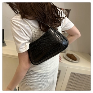 Classic black crocodile pattern baguette shoulder bag worn by a model in a cozy setting
