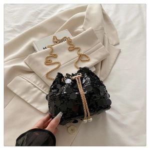 Detail of sequin bucket bag with golden chain drawstring and elegant pearl charms
