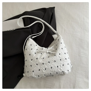 Détail du sac lune blanc avec texture à bulles, imprimé chat et décoration nœud