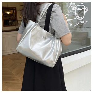 Détail du grand sac cabas argenté avec nœud métallique porté par un mannequin au café