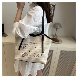 Détail du sac cabas tissé avec broderie de chat, motifs d'étoiles et bandoulières en cuir