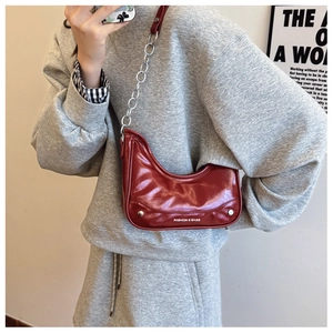 Macro shot of red glossy moon bag with silver chain strap and fashion lettering detail