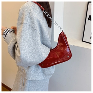 Détail du sac hobo rouge avec chaîne argentée et lettrage blanc sur cuir brillant