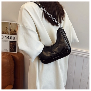 Detail of black glossy crescent bag with silver chain strap and fashion logo