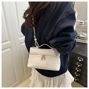 Detail of white woven texture box bag with gold double zippers and structured handle