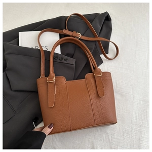 Macro view of caramel brown lychee leather texture on a high-capacity bucket bag