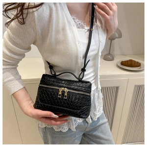 Detail of black woven cross-body bag with double gold zippers and leather handle