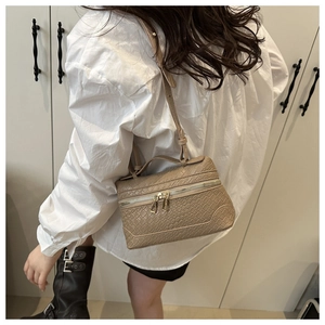 Detail of a beige woven box bag showing double metal zippers and the top handle structure
